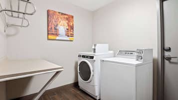 A laundry room with a washing machine, dryer, and a wall-mounted drying rack.