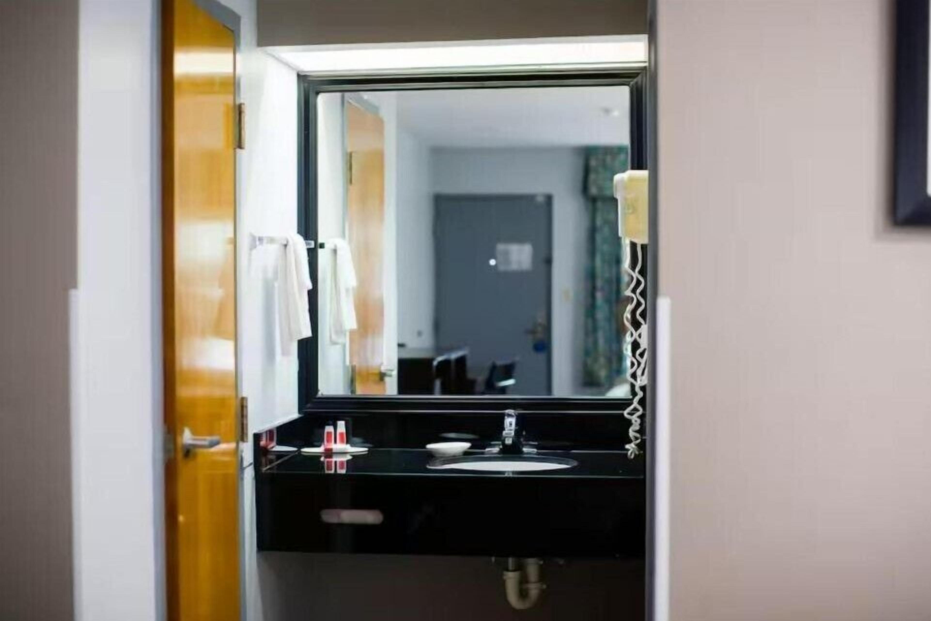 Un baño de hotel con espejo, lavabo y perchero para toallas.