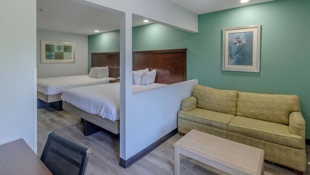Une chambre d’hôtel avec deux lits, un canapé, une petite table et une chaise.