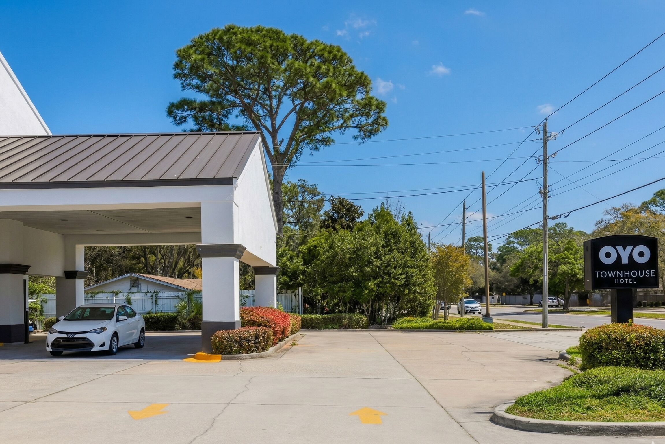 A hotel entrance with a covered parking area, a sign for OYO Townhouse Hotel, and a clear sky.