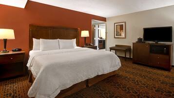 A hotel room with a large bed, two bedside tables with lamps, a television, a desk, and a chair.