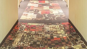 Un pasillo de hotel con pisos alfombrados, puertas a ambos lados y un letrero que indica la habitación número 211.