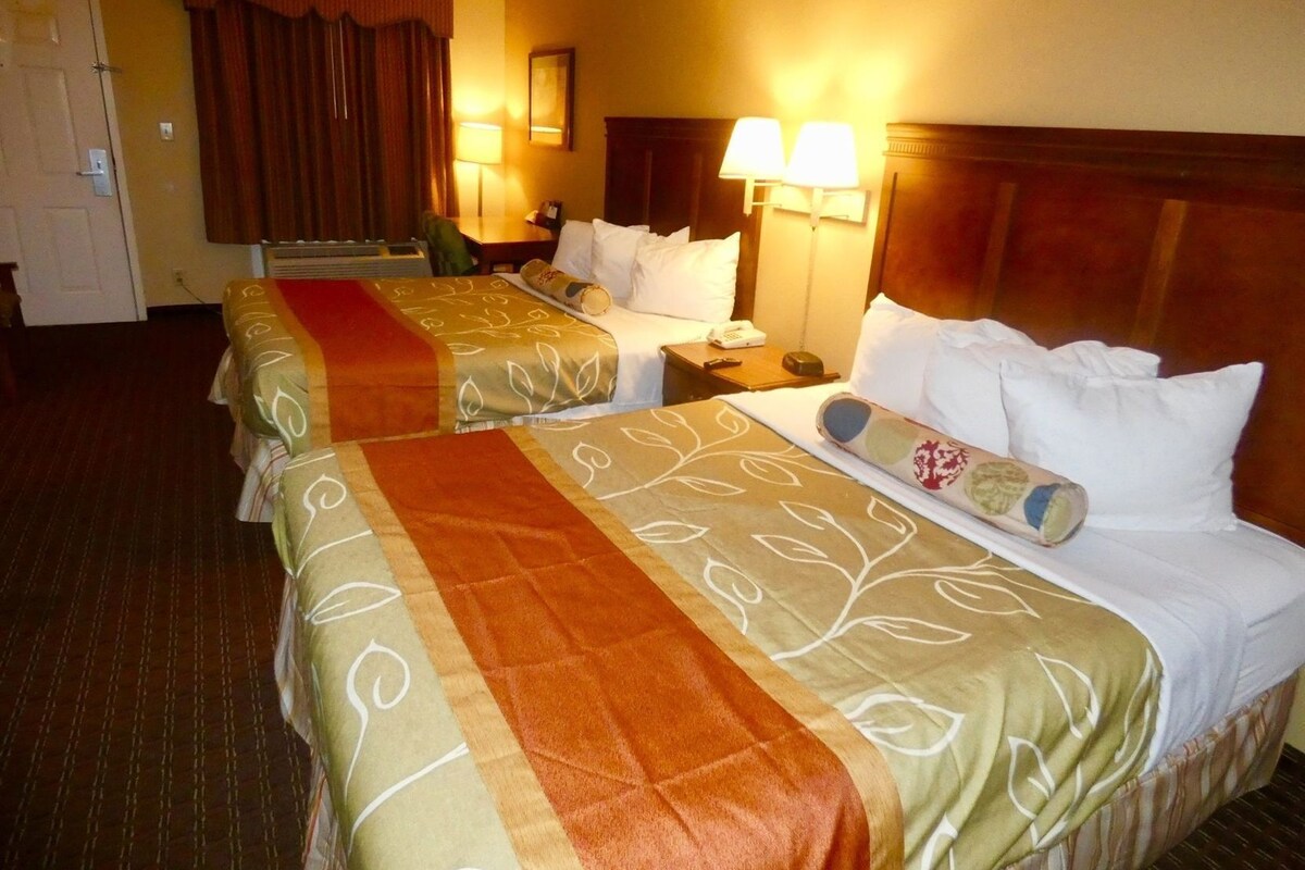 Habitación de hotel con dos camas, un escritorio, un teléfono y dos lámparas.