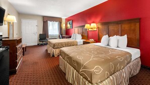 A hotel room with two beds, a desk, a chair, a TV, and a red accent wall. - Americas Best Value Inn Montezuma (Montezuma)