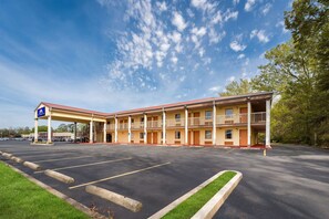 A motel with a gas station, multiple balconies, and a parking lot.