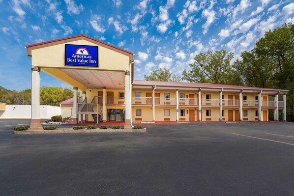 A motel with a large sign, multiple balconies, and a parking lot.