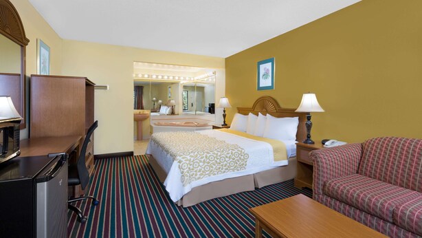 A hotel room with a bed, a desk, a chair, a sofa, and a bathroom visible through an open door. - Days Inn by Wyndham Biscoe (Biscoe)