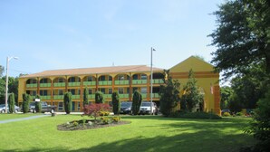 A multi-story motel with a yellow facade, green balconies, and a well-maintained lawn.