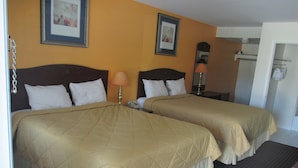 A hotel room with two beds, each with a headboard, a bedside lamp, and a framed picture on the wall.