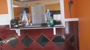 A reception desk with a mirror, a key drop box, a telephone, and a sign indicating an exit.