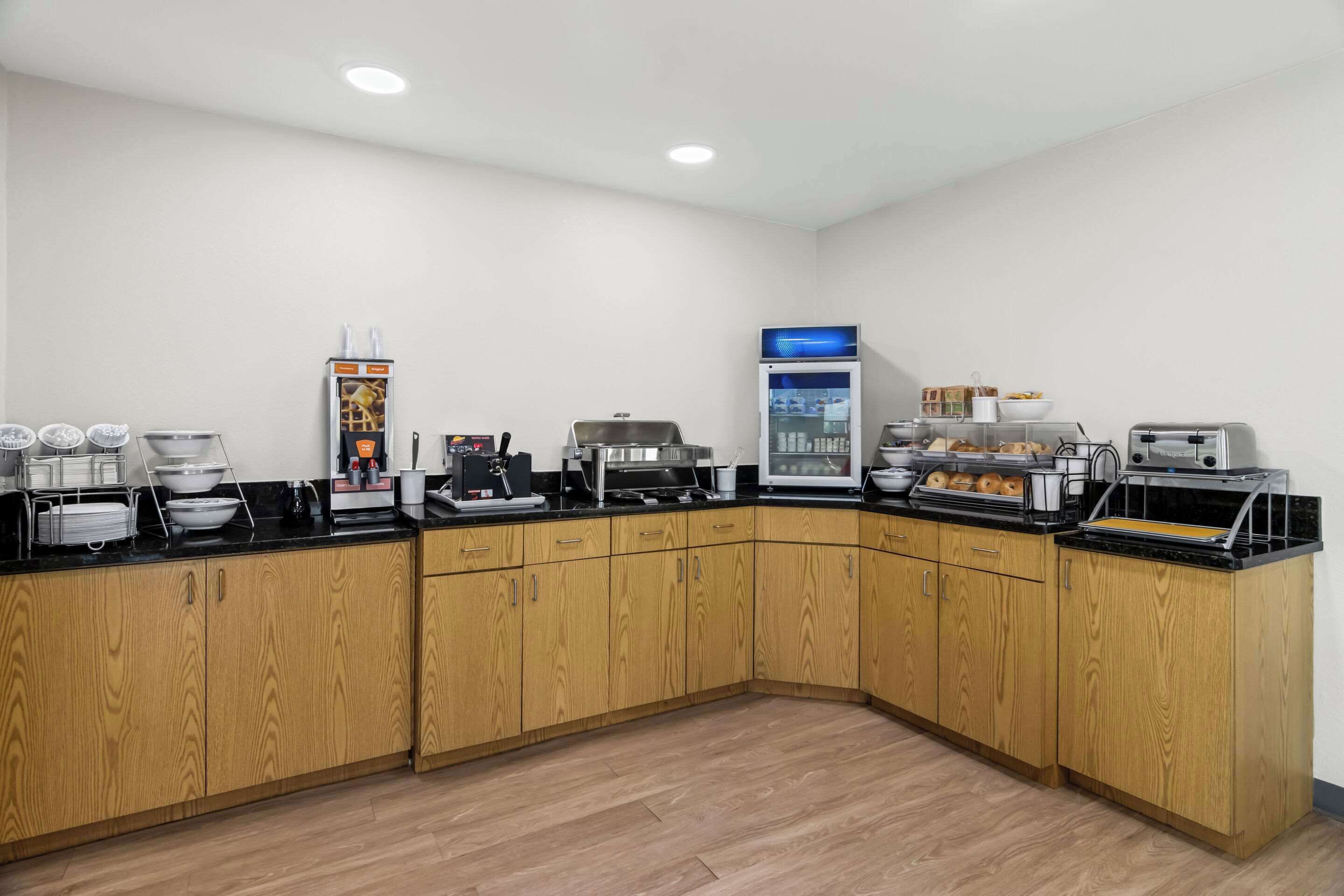 A kitchen area with wooden cabinets, a coffee machine, a refrigerator, and a toaster.
