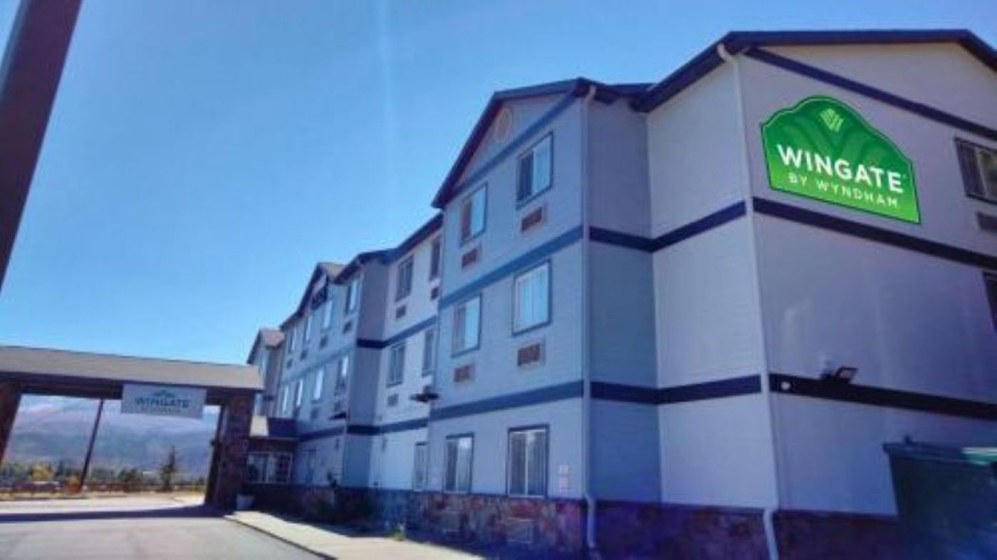 A multi-story hotel building with a prominent green and white sign indicating it is a Wyndham property.