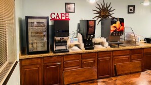 Una zona de café con una máquina de café, un refrigerador y un dispensador de jugo.