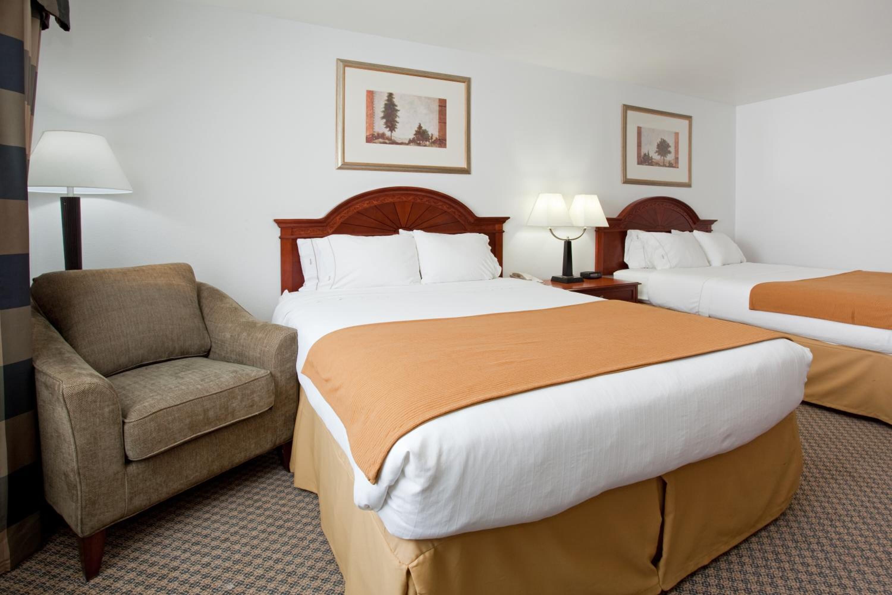 Une chambre d’hôtel avec deux lits, un canapé et une lampe.