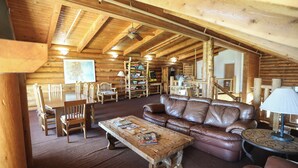 A log cabin interior with a wooden dining table, leather sofa, and bookshelves. - The Boulder Creek Lodge (Nederland)
