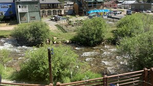 A riverside view of a town with a riverside restaurant and a building labeled "SMOKEHOUSE & BREWERY." - The Boulder Creek Lodge (Nederland)