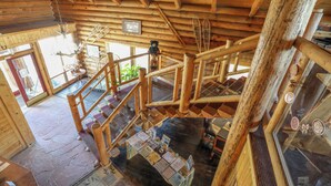 A wooden staircase with a wooden railing, a wooden ceiling, and a stone floor. - The Boulder Creek Lodge (Nederland)