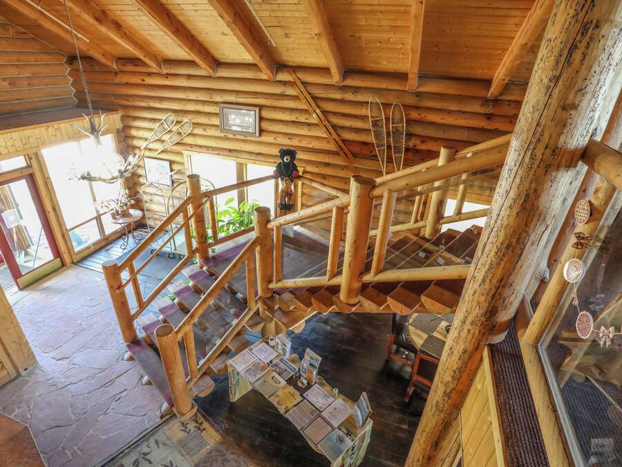 A wooden staircase with a wooden railing, a wooden ceiling, and a stone floor.