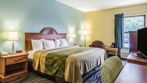 A hotel room with a bed, bedside tables, lamps, a chair, a desk, and a television. - Econo Lodge Darien (Darien)