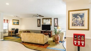 A living room with a sofa, TV, and a red vending machine. - Econo Lodge Darien (Darien)