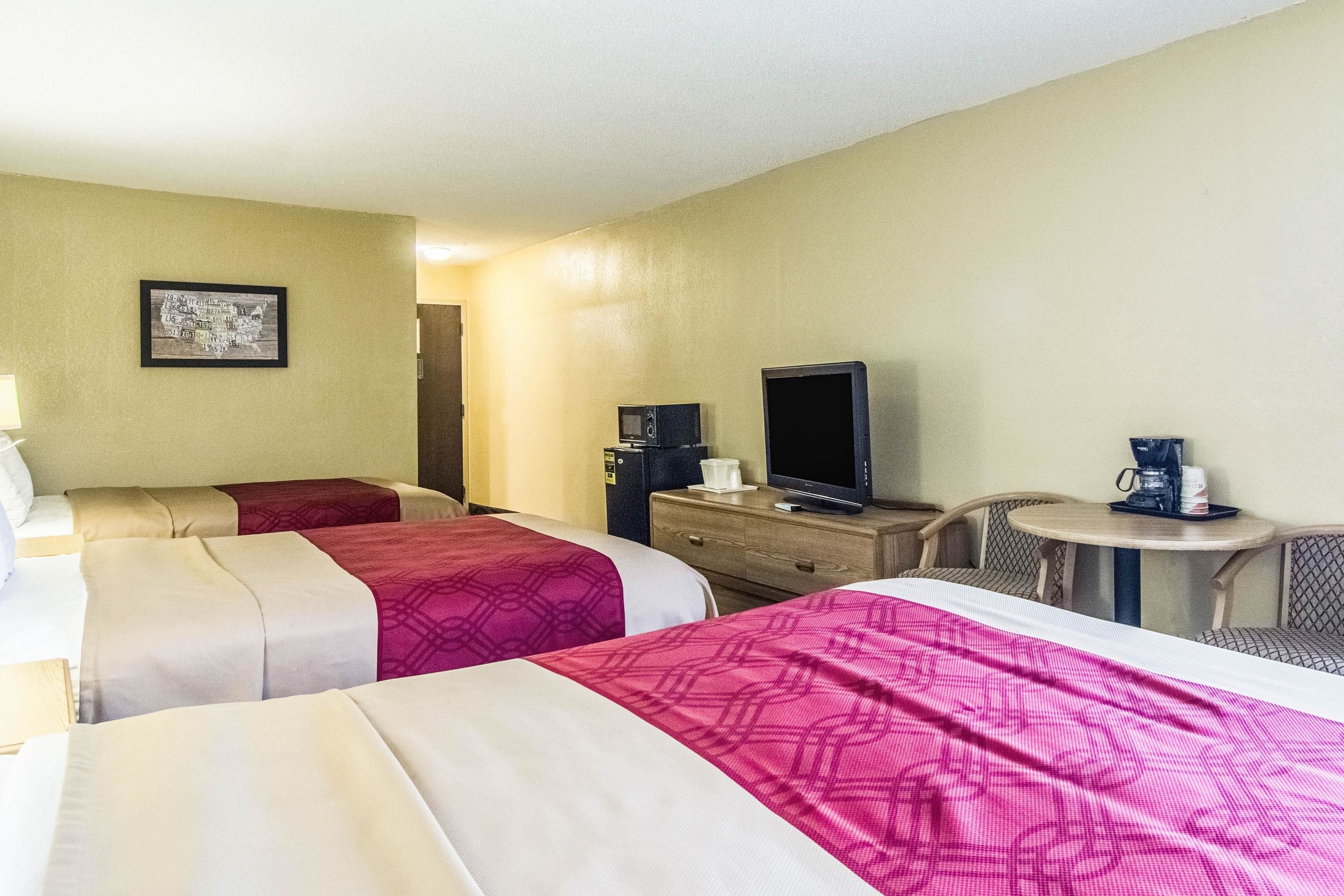 Habitación de hotel con dos camas, televisión, cafetera y una mesita.
