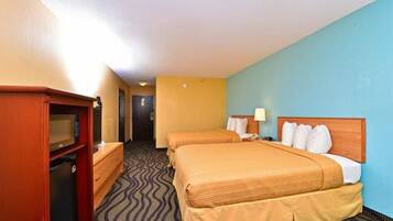 A hotel room with two beds, a desk with a computer, and a microwave.
