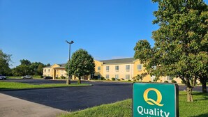 A Quality Inn by Choice Hotels with a clear sky, a parking lot, and a building with multiple windows. - Quality Inn Kingdom City I-70 (Kingdom City)