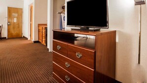 A hotel room with a wooden dresser, a flat-screen TV, a door, and a hallway. - Quality Inn Kingdom City I-70 (Kingdom City)