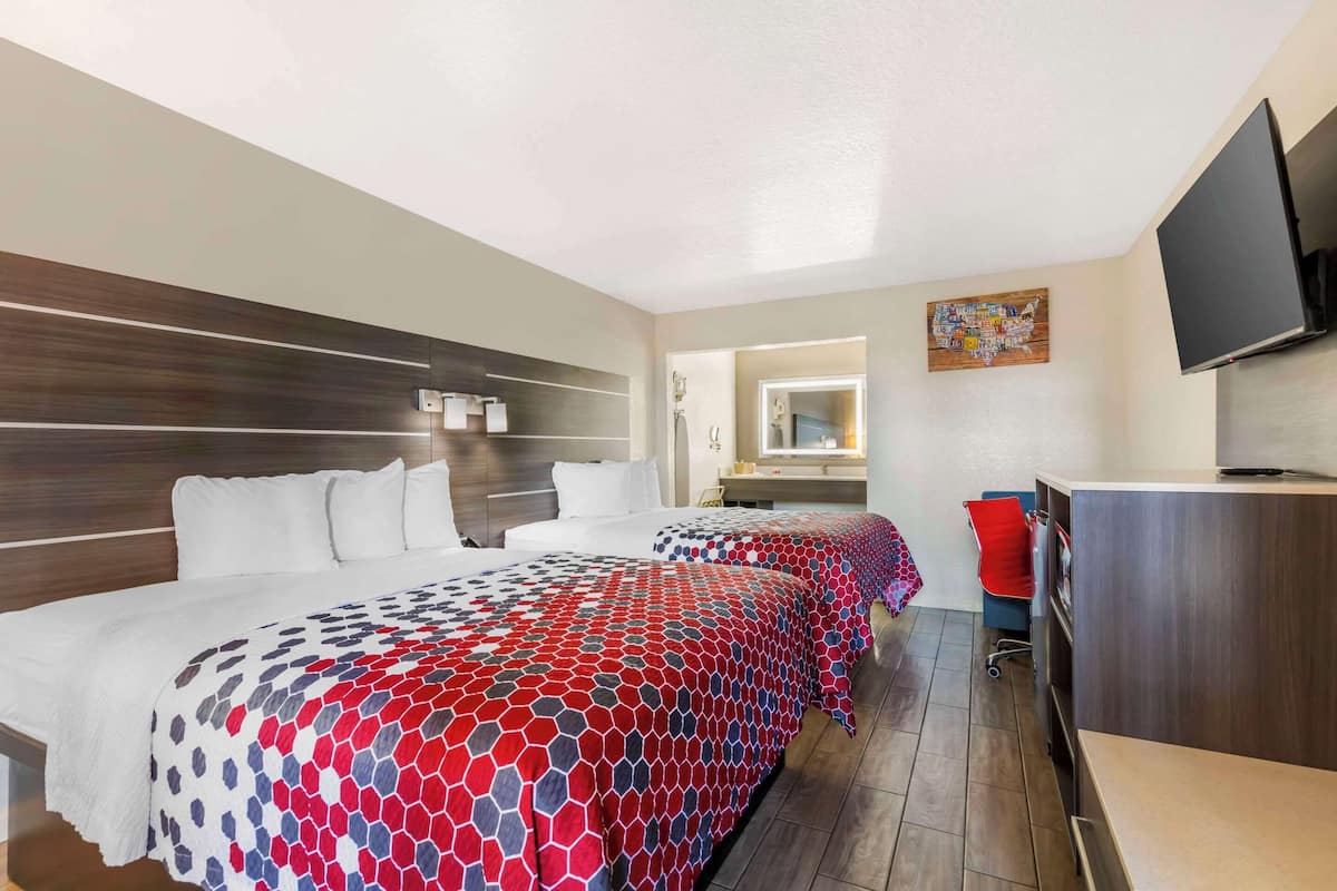 A hotel room with a large bed, a desk, a chair, a television, and a map artwork on the wall.