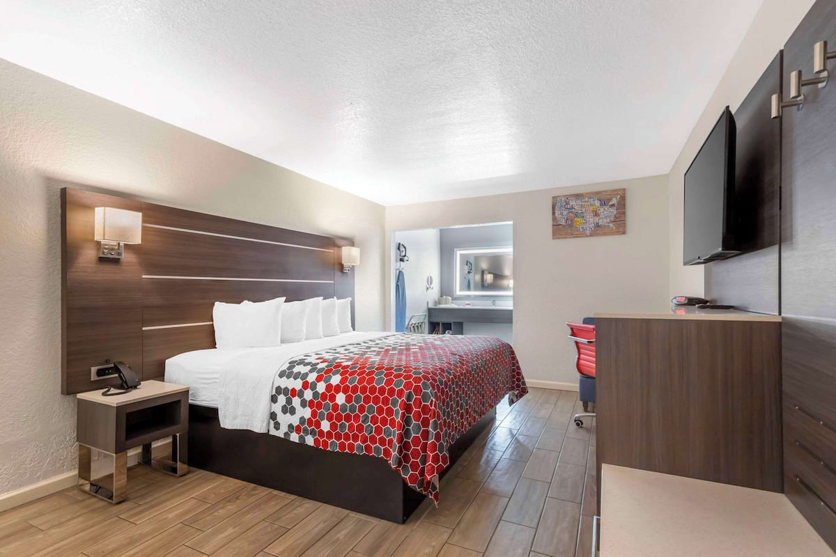 A modern hotel room with a large bed, bedside table, and a flat-screen TV.