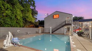 A swimming pool area with a lifeguard chair, a changing room, and a staircase leading to a building with an 'EconoLodge' sign. - Econo Lodge Inn & Suites Near Lackland AFB (San Antonio)
