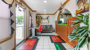 A reception area with a desk, a sofa, and a large plant. - Econo Lodge Inn & Suites Near Lackland AFB (San Antonio)