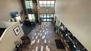 Eine großzügige Lobby mit Holzdielenboden, einer Rezeption und einer Sitzecke mit einer Kandelaber.