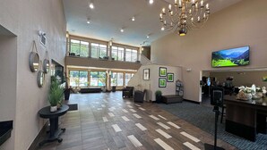 Eine geräumige Lobby mit hoher Decke, einem Chandelier, einem großen Bildschirm und einer Treppe zu einer oberen Ebene.