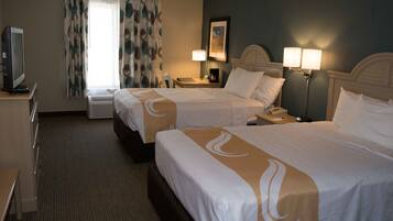 A hotel room with two beds, a desk, a TV, a lamp, and a painting on the wall.