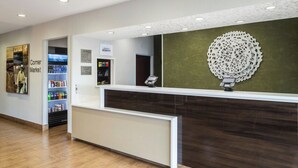 A hotel reception area with a reception desk, a corner market, and a decorative wall piece. - Fairfield Inn by Marriott Richmond (New Paris)
