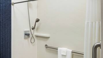 A shower area with a handrail, a towel rack, and a showerhead.