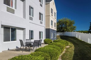 A modern building with a patio area featuring a table and chairs. - Fairfield Inn by Marriott Richmond (New Paris)
