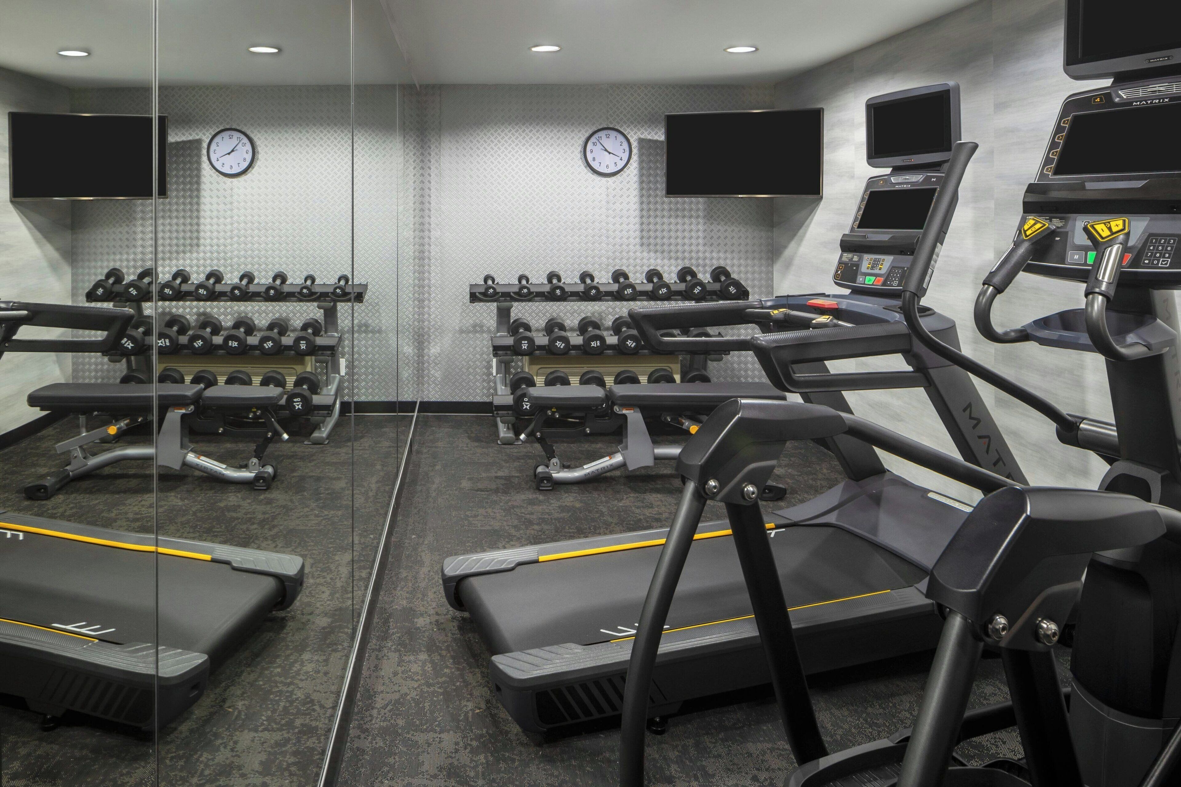 A gym with treadmills, dumbbells, and weight machines.