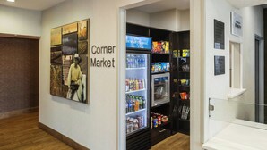 A corner market with refrigerated and non-refrigerated food sections, a vending machine, and a wall with informational posters. - Fairfield Inn by Marriott Richmond (New Paris)