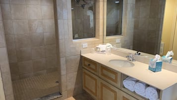 A modern bathroom with a walk-in shower, a large mirror, and a vanity with a sink and towel storage.