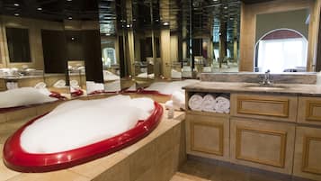A modern bathroom with a large mirror, a red bathtub, and neatly folded towels.