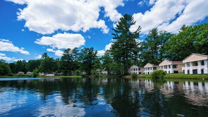 A lakeside view of a resort with multiple buildings, a calm lake, and surrounding greenery. - Paradise Stream Resort (Cresco)