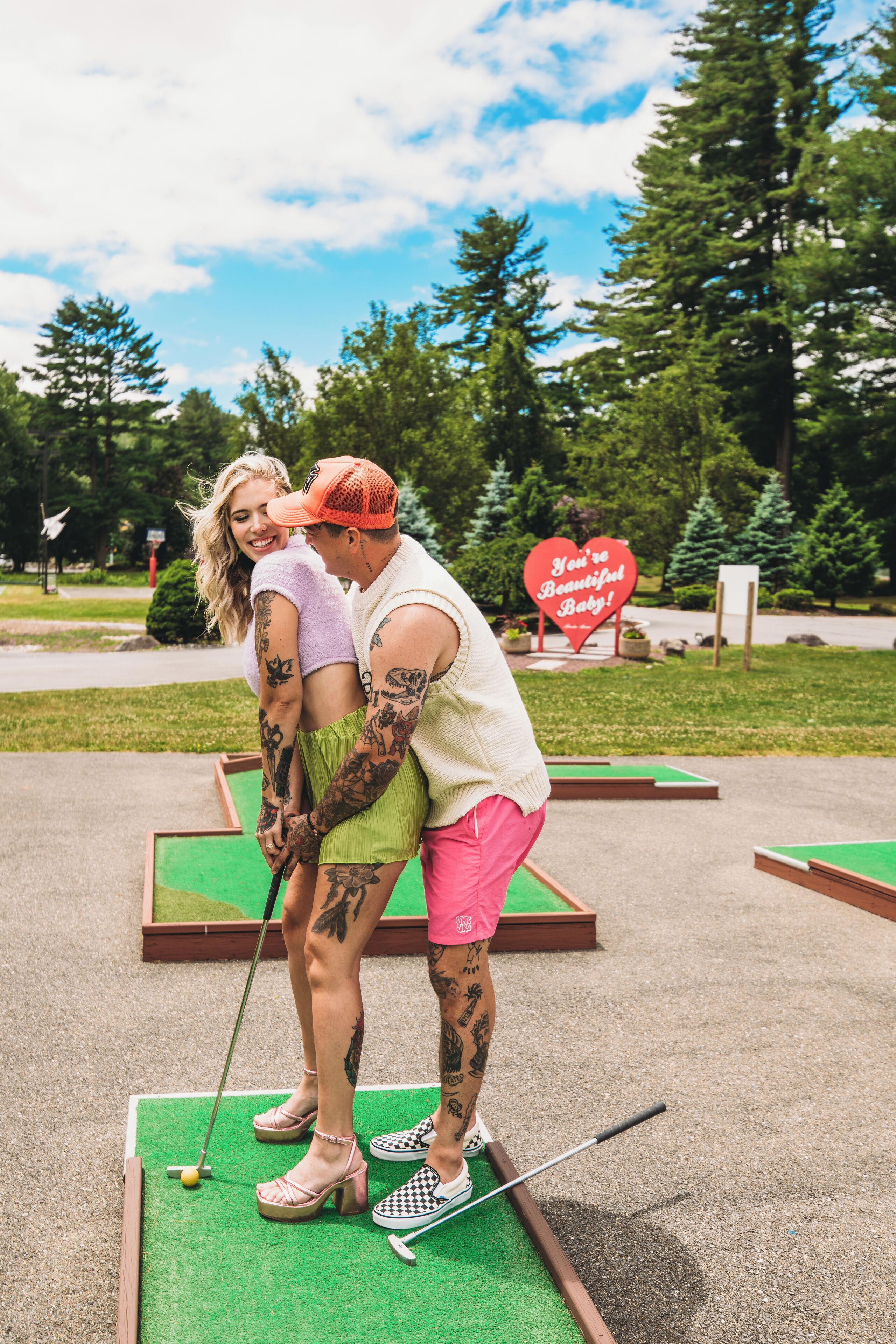 Et par spiller minigolf, med et hjerteformet skilt i baggrunden.