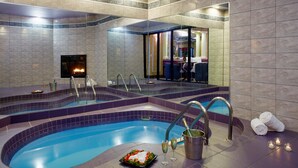 A spa area with a pool, seating, and a fireplace. - Paradise Stream Resort (Cresco)