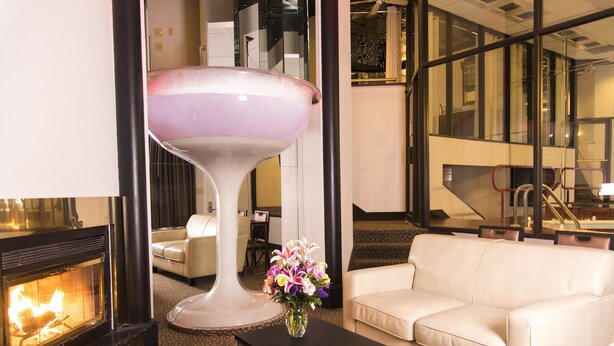A modern living room with a fireplace, a white sofa, a black coffee table with a vase of flowers, and a large decorative glass object. - Paradise Stream Resort (Cresco)