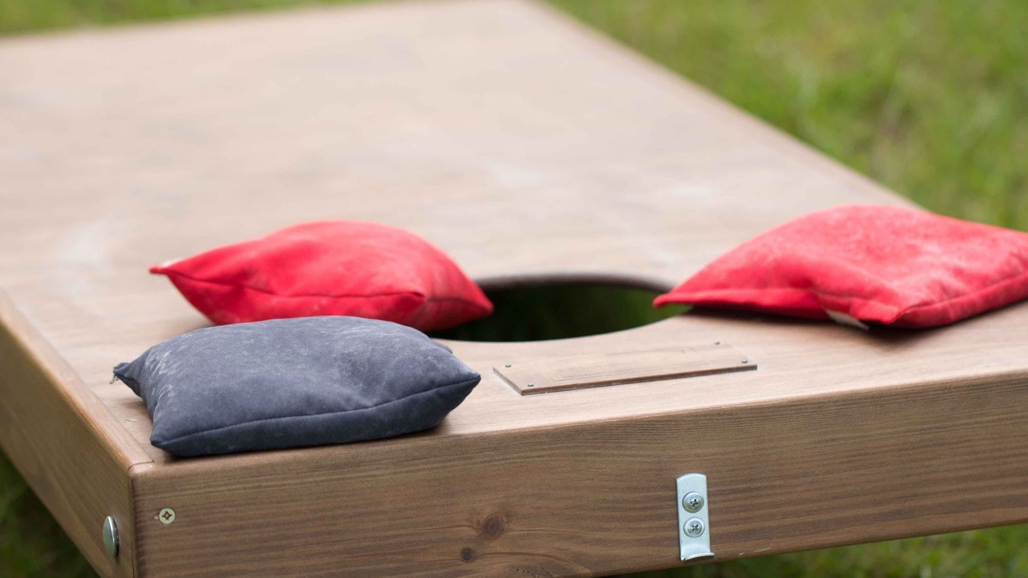Un banco de madera con un hueco en el centro y dos cojines, uno rojo y otro azul, colocados encima.
