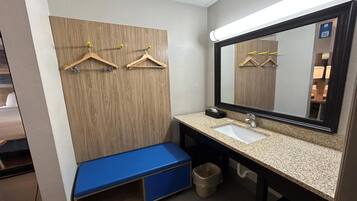 Un baño con pared de paneles de madera, un lavamanos, un espejo y un banco azul.