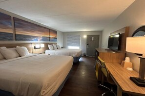 Een hotelkamer met twee bedden, een bureau met lamp, een televisie en kunstwerken aan de wanden.