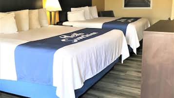 Ein Hotelzimmer mit zwei Betten, einem Schreibtisch und einem Nachttisch.